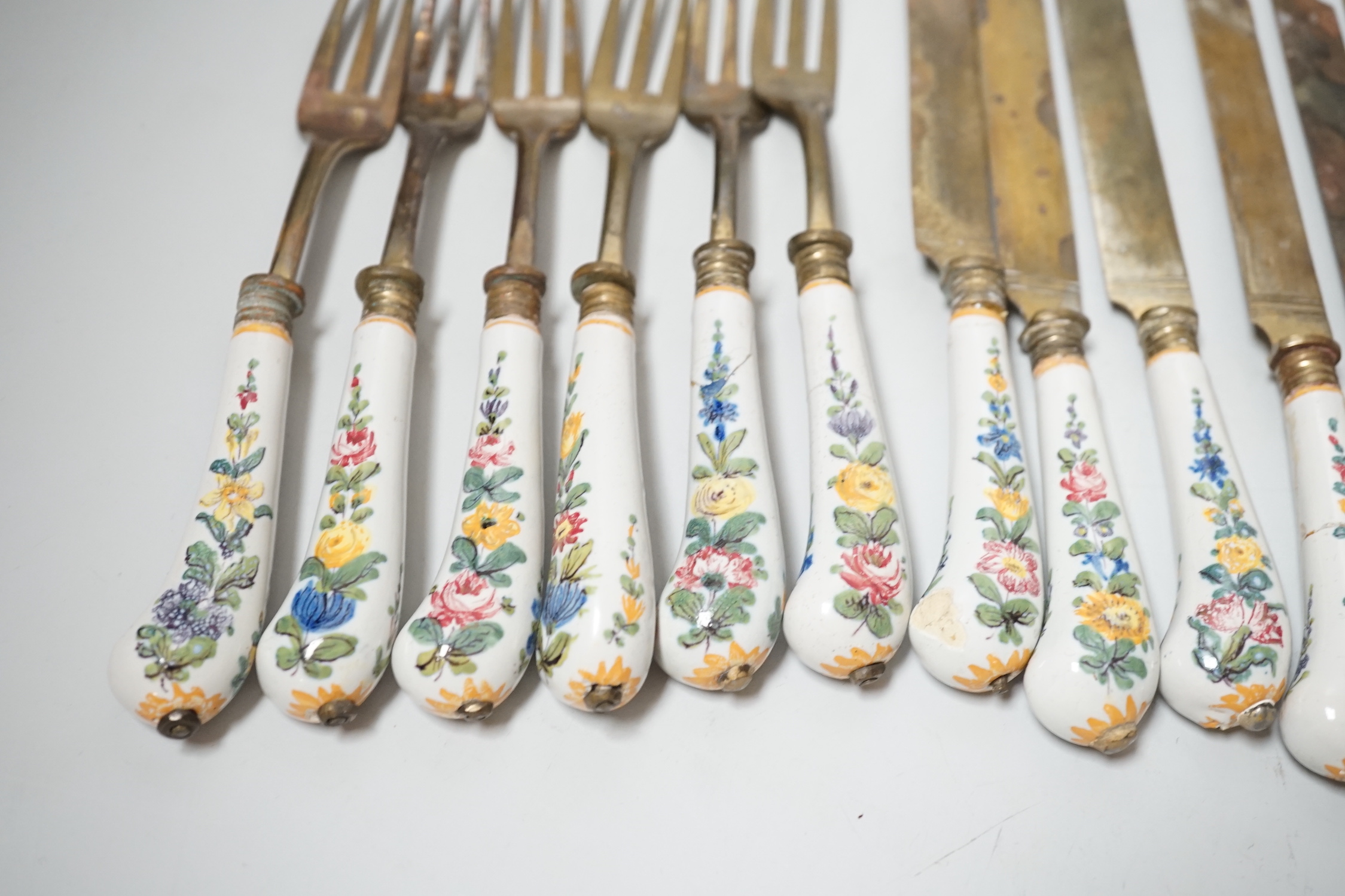 Six pairs of French Faience pistol grip handled knives and forks